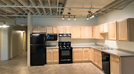 A kitchen with black appliances and wooden cabinets.