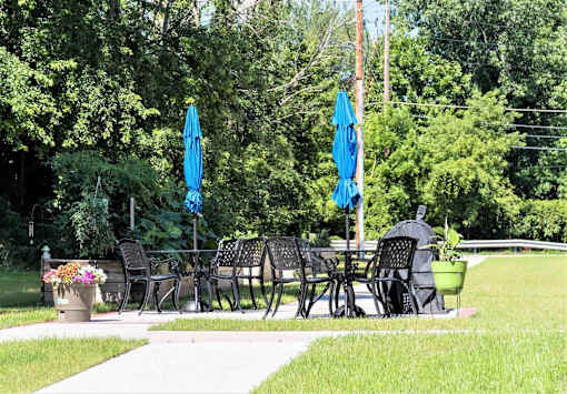 A patio with black chairs and blue umbrellas.