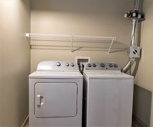 Two white washing machines in a small laundry room.