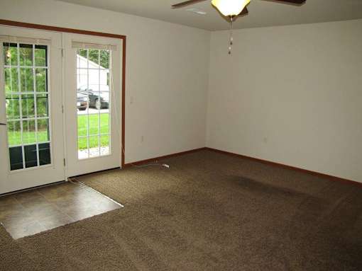 A room with a carpeted floor and a ceiling fan.