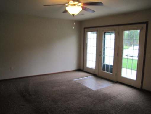 A room with a ceiling fan and carpeted floor.