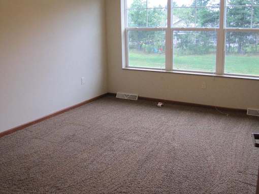 A room with a carpeted floor and a large window.