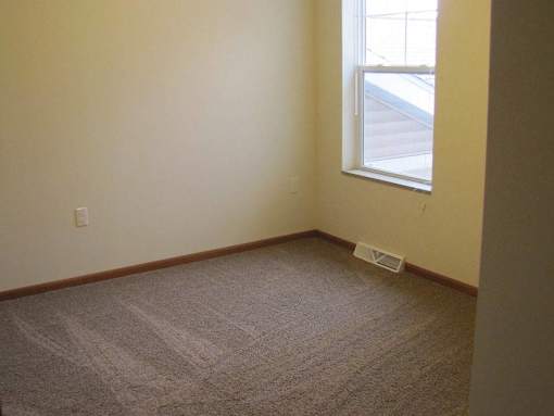 A room with a carpeted floor and a window.