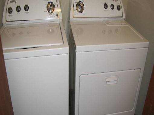 Two white washing machines in a small room.