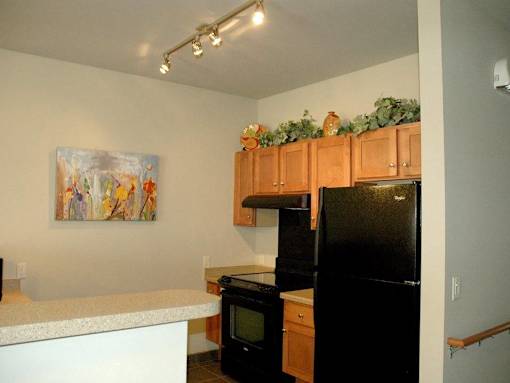 A kitchen with a black fridge and a painting on the wall.