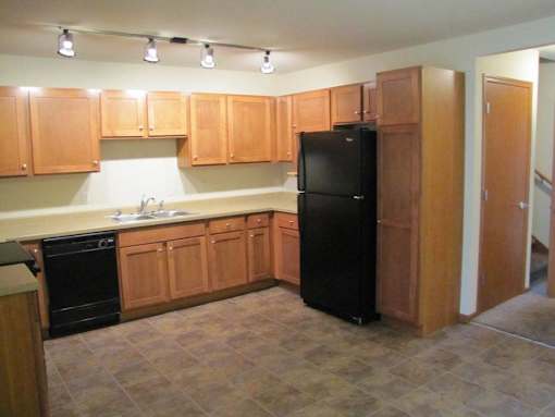A kitchen with wooden cabinets and a black refrigerator.