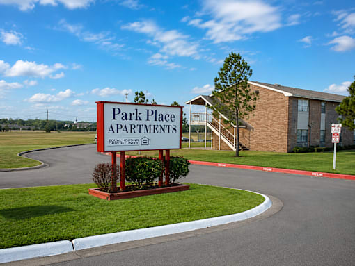 A sign for Park Place Apartments stands in front of a brick building.