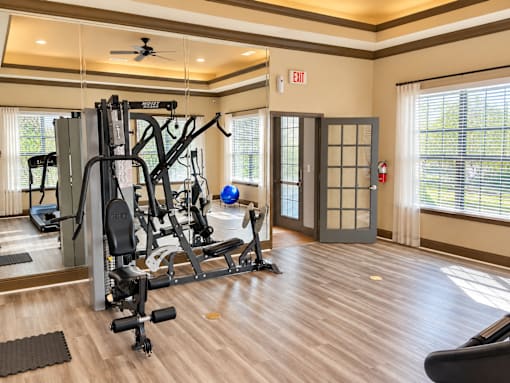 A gym with a variety of equipment including a weight bench, a treadmill, and a stationary bike.