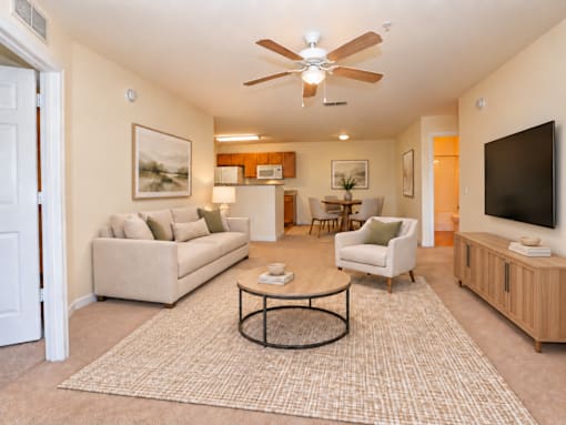 A living room with a beige couch, a coffee table, and a ceiling fan.