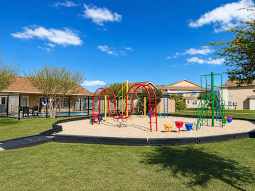 A playground with a red swing set and a yellow slide.