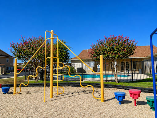 A playground with a yellow climbing frame and blue and red sandpits.