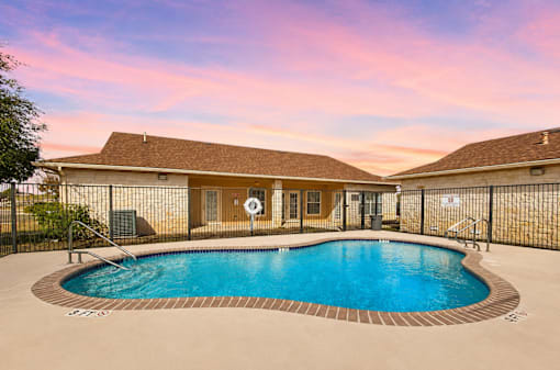 A swimming pool in a backyard with a house in the background.
