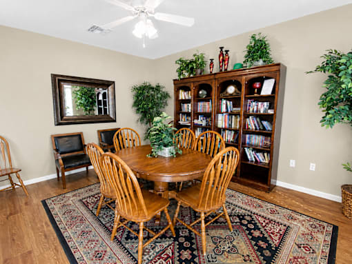 A room with a wooden table surrounded by chairs and a bookcase with books.