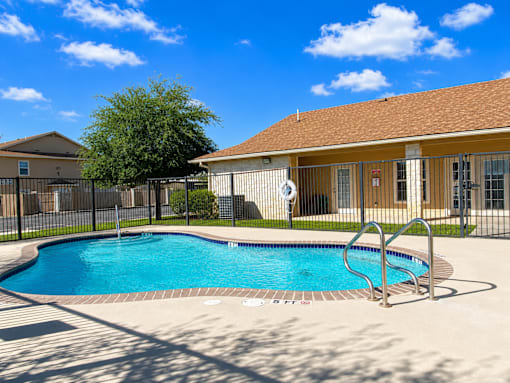 A small pool in front of a house with a fence around it.