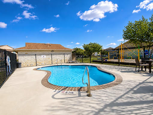 A small pool with a brown fence and a blue sky in the background.
