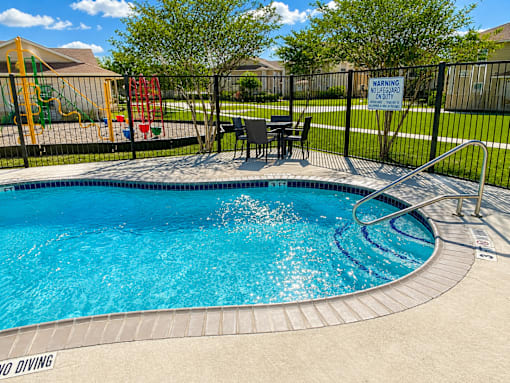 A pool with a warning sign on the fence.