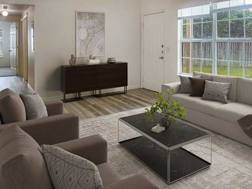 A living room with a brown sofa, a grey armchair, a black coffee table, and a white door.
