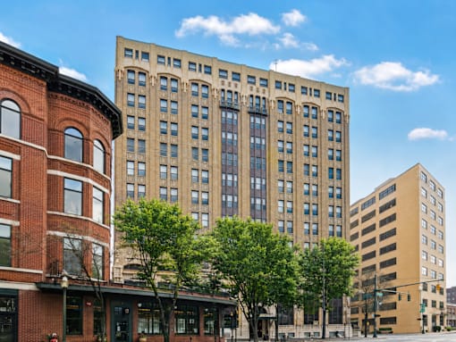 A large building with many windows sits in the middle of a city street.