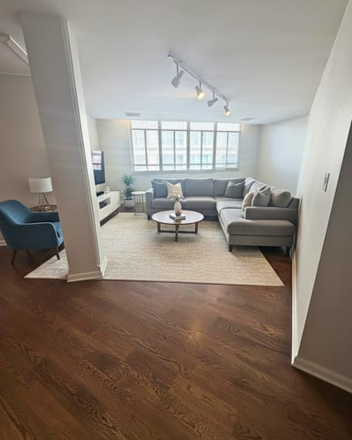 A living room with a grey couch, a blue chair, and a white coffee table.