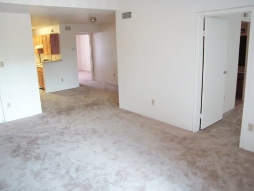 an empty living room with white walls and carpet