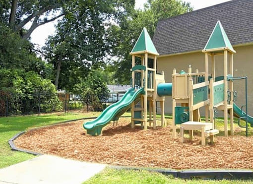 A playground with a green slide and wooden structure.