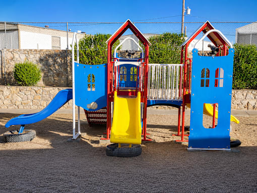 A playground with a blue slide and two red and blue houses.