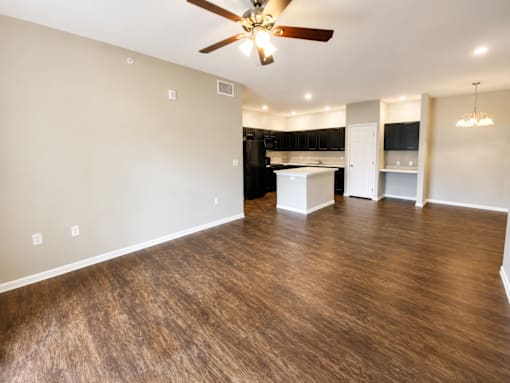 A room with a ceiling fan and wooden flooring.
