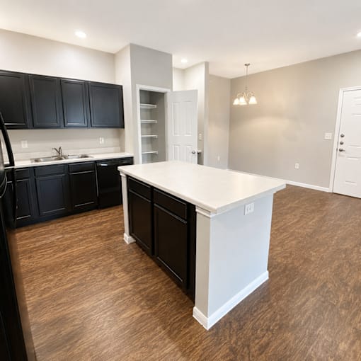 A kitchen with black cabinets and a white island.