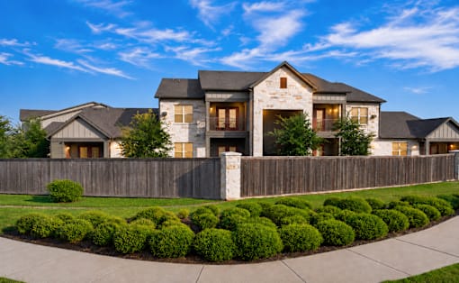 A large, modern house with a stone facade and a wooden fence.