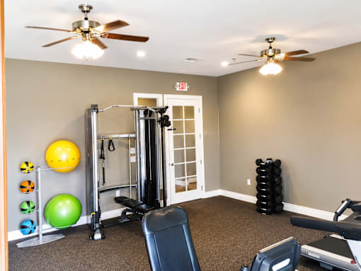 A gym room with a variety of equipment including a treadmill, weights, and a bench.