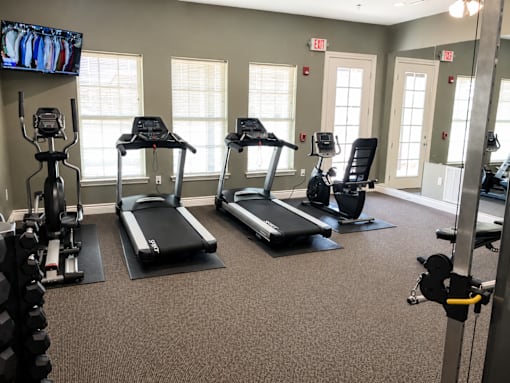 A gym with treadmills, elliptical machines, and a television.