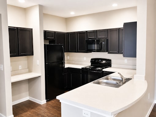 A kitchen with black appliances and white countertops.