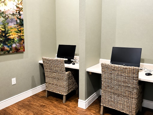 Two brown chairs are in front of two computers.