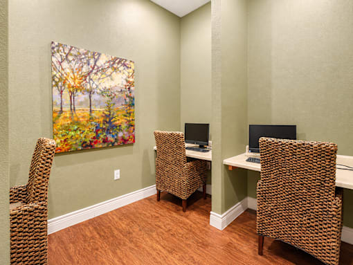 A room with a painting of a tree and three chairs.