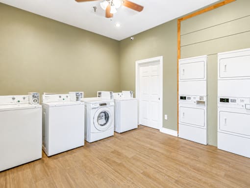 A room with a row of washing machines on the left and a row of dryers on the right.