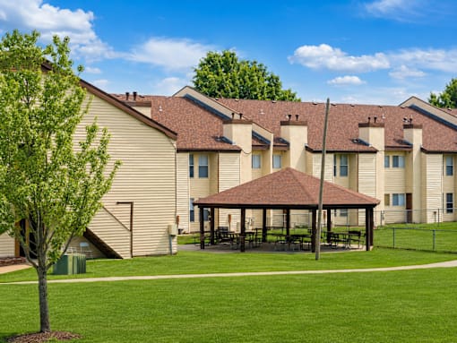 A tree stands in front of a building with a covered patio.