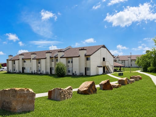 A row of houses with a grassy front yard and large rocks in the foreground.
