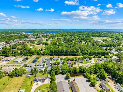 A bird's eye view of a residential area with houses, trees, and a body of water.