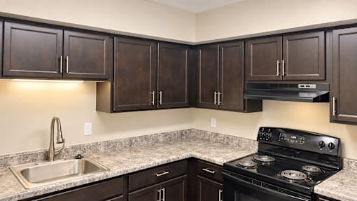A kitchen with dark brown cabinets and a black stove top oven.