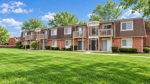A row of red brick apartment buildings with green lawns in front.