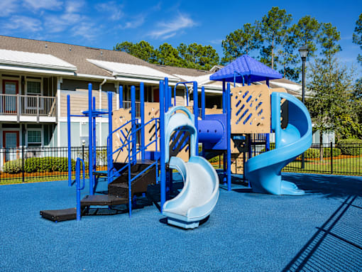 A playground with a blue slide and a wooden structure.