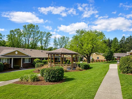 A sunny day at a park with a gazebo and a walking path.