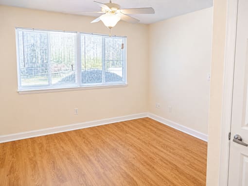 A room with a ceiling fan and a window with blinds.