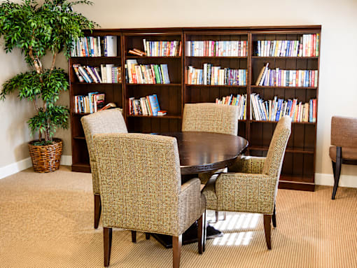 A room with a large bookshelf filled with books and a table with chairs.