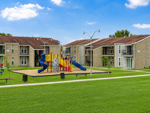A playground with a slide and swings in front of apartment buildings.