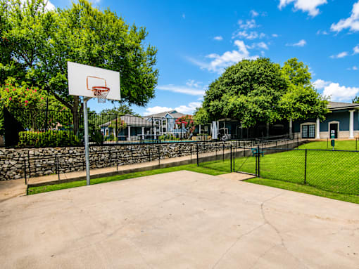 A basketball court with a hoop and a fence.