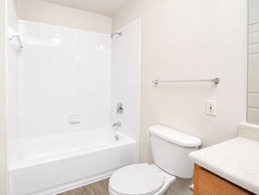 A white bathroom with a toilet, tub, and towel rack.