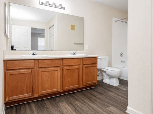 A bathroom with a wooden vanity and a white toilet.