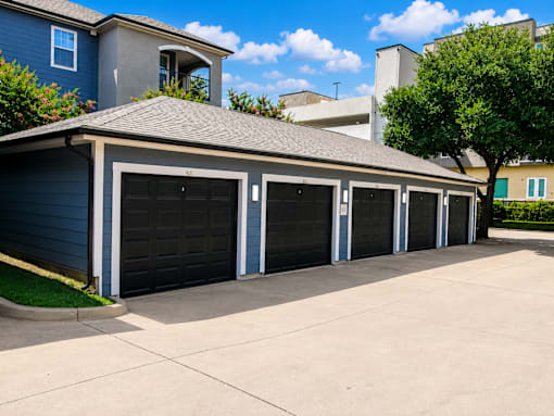 A row of black garage doors in front of a blue house.