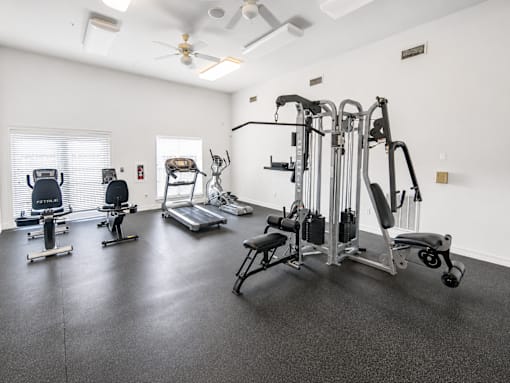 A spacious gym with a variety of equipment including treadmills, elliptical machines, and weight machines.